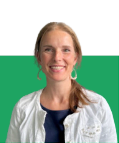 Sylvia_Reh_Kassenwartin Porträt von Sylvia Reh, Kassenwartin, lächelnd im weißen Blazer vor einem grünen Hintergrund.